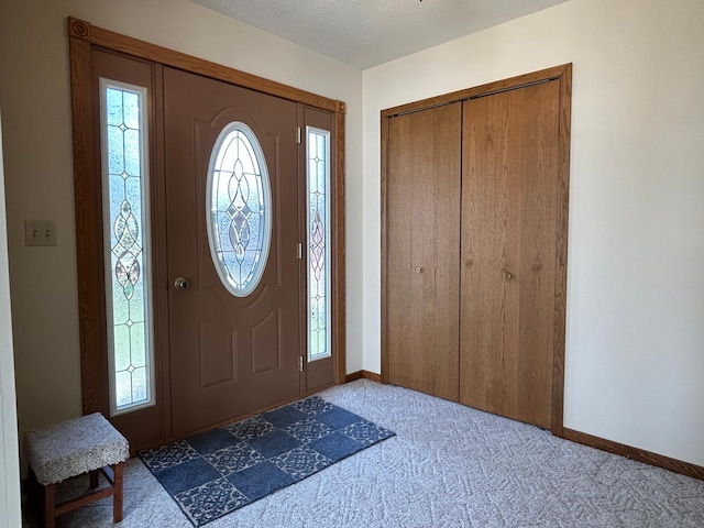carpeted foyer entrance with baseboards and a healthy amount of sunlight
