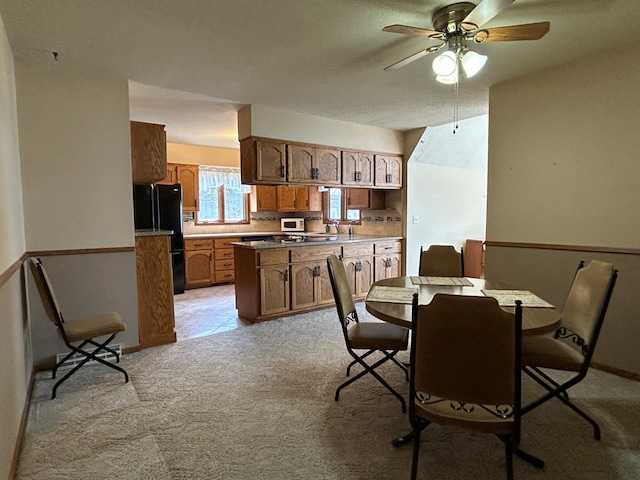 dining space featuring ceiling fan, light carpet, and baseboards