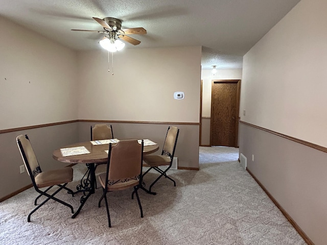 dining space featuring carpet flooring, a ceiling fan, a textured ceiling, and baseboards