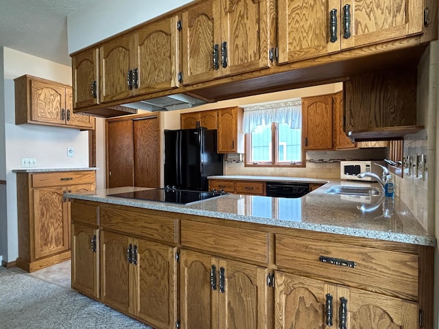 kitchen featuring brown cabinets, a sink, light stone counters, black appliances, and a peninsula