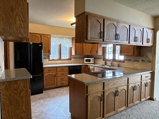 kitchen featuring a sink, a peninsula, black appliances, and a healthy amount of sunlight