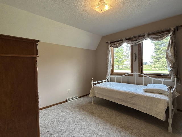 bedroom with carpet floors, a textured ceiling, baseboards, lofted ceiling, and visible vents