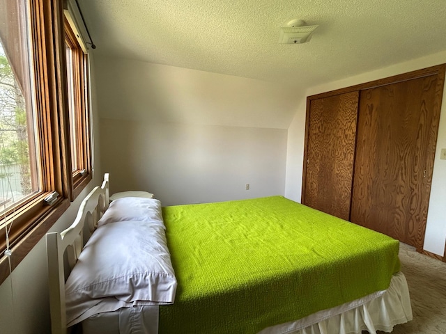 carpeted bedroom featuring a textured ceiling and a closet