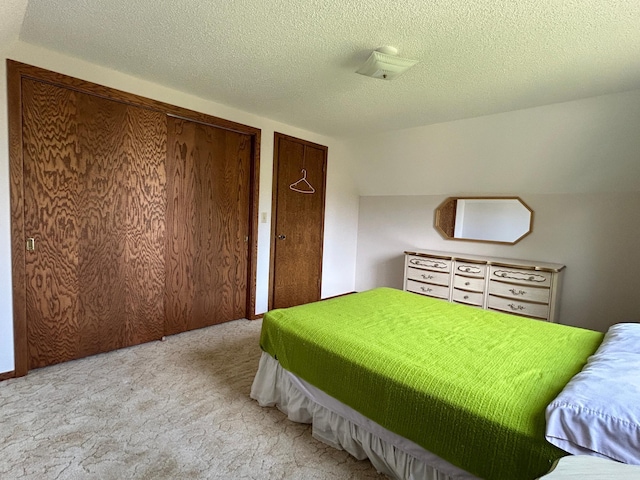 carpeted bedroom featuring a textured ceiling and multiple closets