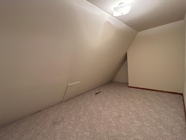 bonus room featuring a textured ceiling, visible vents, light carpet, and vaulted ceiling