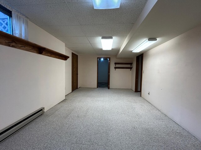 finished below grade area featuring a baseboard heating unit and light colored carpet