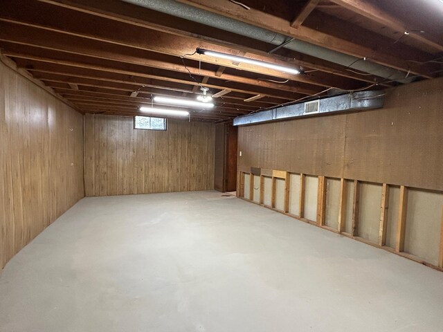 basement featuring wood walls and visible vents