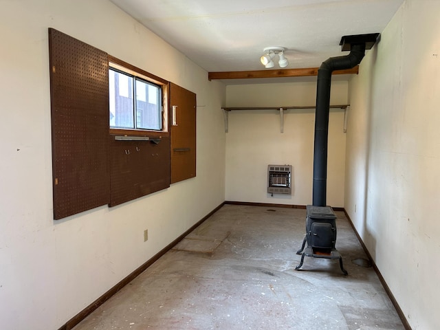 spare room featuring heating unit, baseboards, and a wood stove