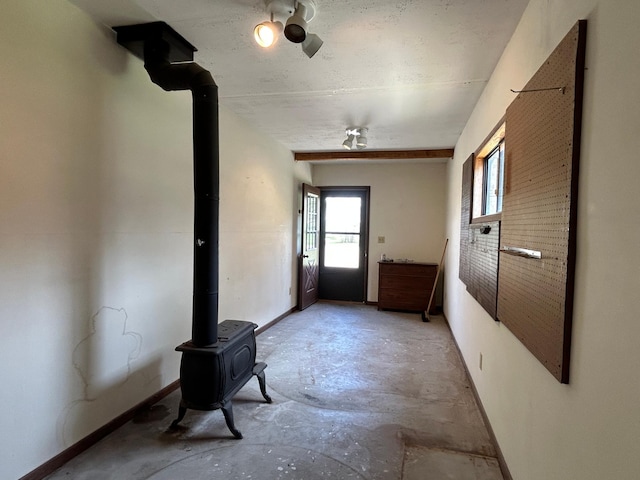 interior space featuring baseboards, concrete floors, and a wood stove