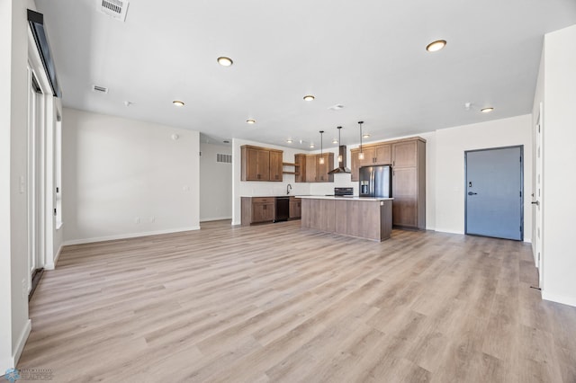 kitchen featuring wall chimney range hood, stainless steel fridge, black dishwasher, open floor plan, and visible vents