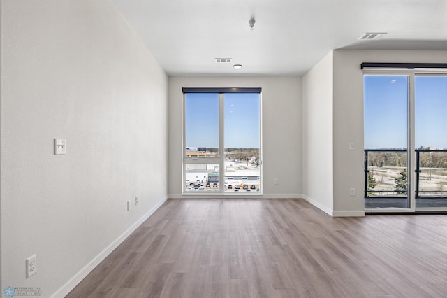 spare room with baseboards, visible vents, and wood finished floors