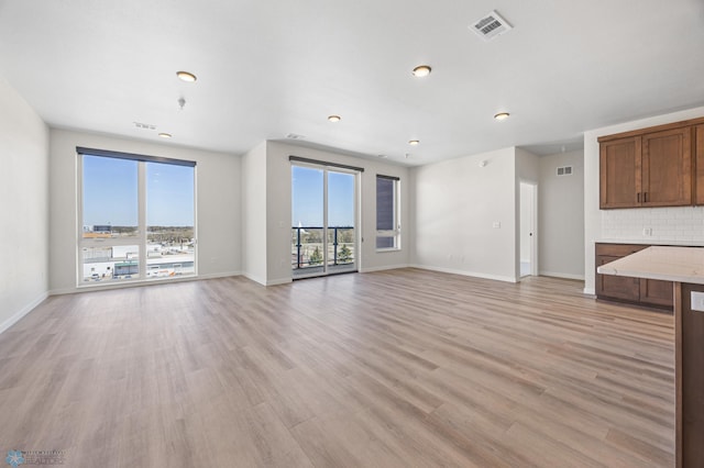 unfurnished living room with visible vents, baseboards, and light wood-type flooring