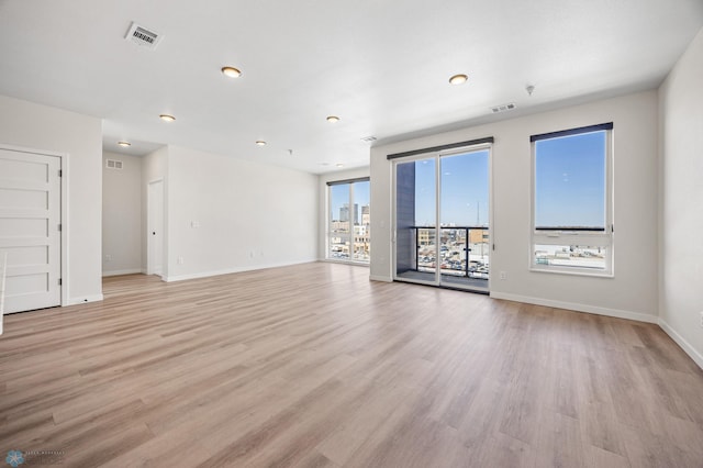 unfurnished living room with baseboards, visible vents, and light wood-type flooring