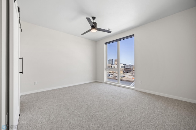 spare room with a city view, carpet floors, baseboards, and a ceiling fan