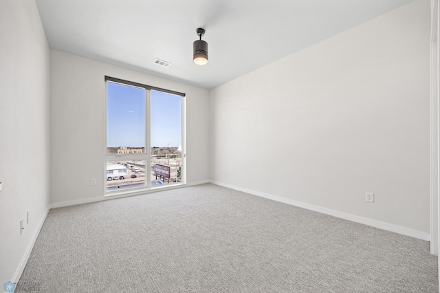 carpeted spare room featuring baseboards and visible vents