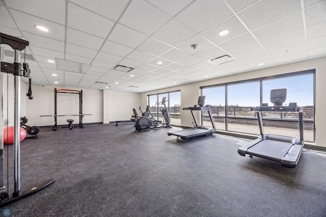 exercise room with baseboards and a drop ceiling