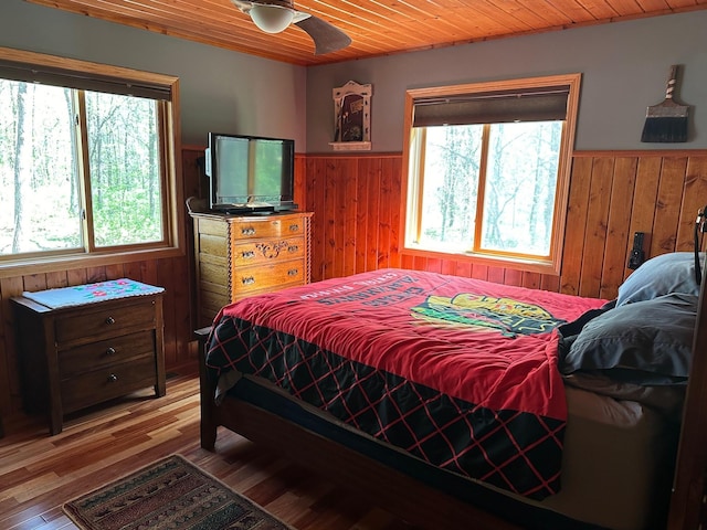 32305 W St, Breezy Point, MN 56472 - bedroom featuring wooden walls, wainscoting, wood ceiling, light wood-style floors, and ceiling fan