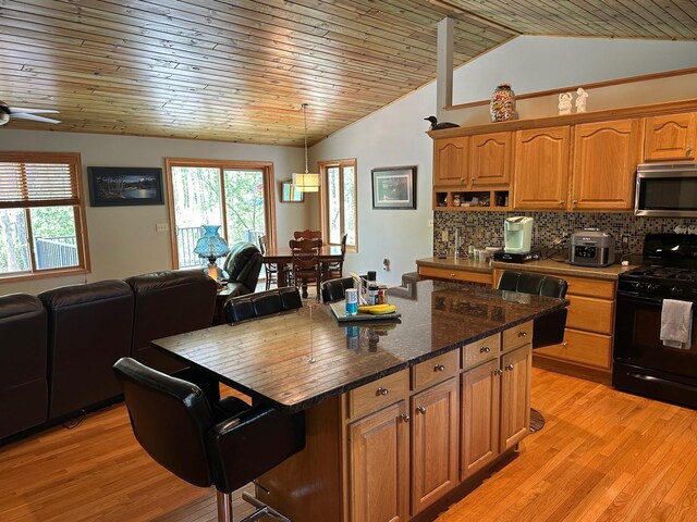 32305 W St, Breezy Point, MN 56472 - kitchen featuring black range with gas cooktop, stainless steel microwave, vaulted ceiling, open floor plan, and healthy amount of natural light