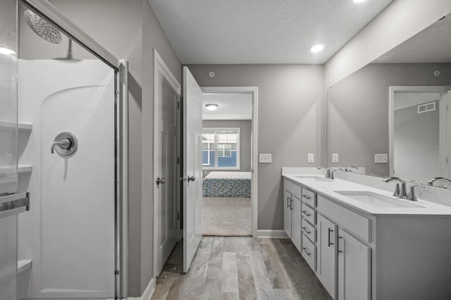 1144 Middlefield Rd, Medina, MN 55340 - ensuite bathroom with a textured ceiling, a stall shower, wood finished floors, double vanity, and baseboards