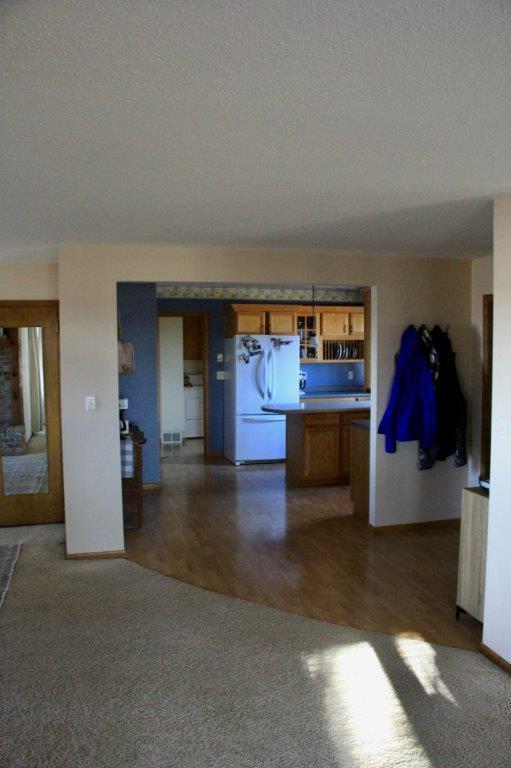 kitchen with brown cabinetry, freestanding refrigerator, visible vents, a textured ceiling, and carpet