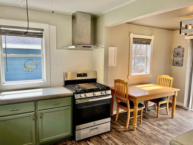 kitchen with stainless steel gas stove, green cabinets, dark wood-type flooring, wall chimney exhaust hood, and a wealth of natural light