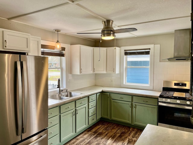 kitchen with wall chimney range hood, green cabinetry, a sink, stainless steel appliances, and dark wood-type flooring