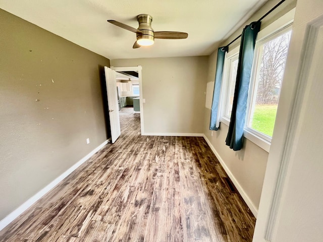 empty room featuring baseboards, ceiling fan, and wood finished floors