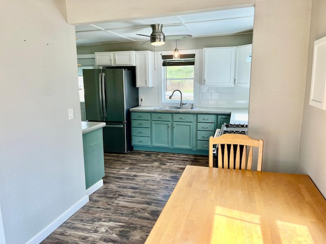 kitchen with freestanding refrigerator, decorative backsplash, ceiling fan, a sink, and dark wood finished floors