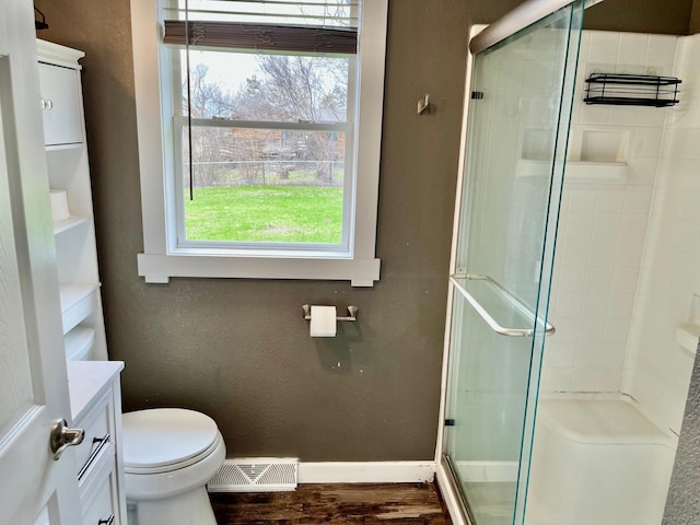 bathroom featuring visible vents, a shower stall, wood finished floors, baseboards, and toilet
