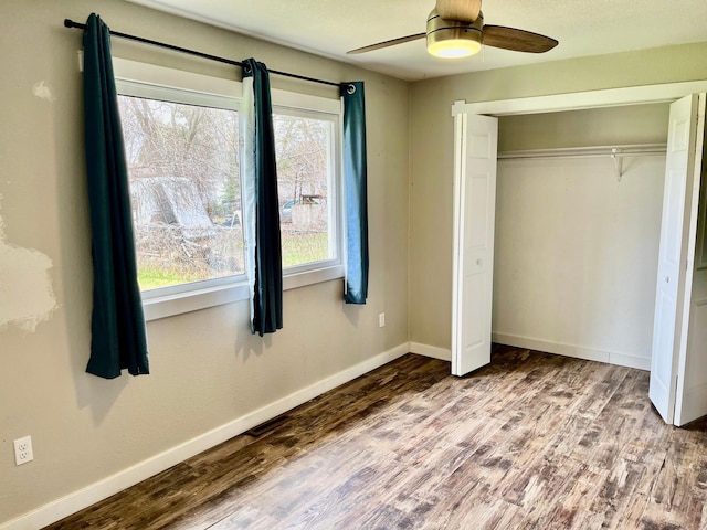 unfurnished bedroom featuring baseboards, a ceiling fan, wood finished floors, and a closet