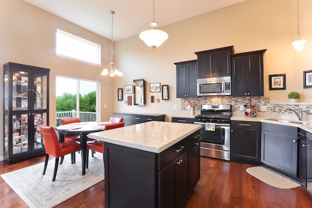 6942 151st St, Savage, MN 55378 - kitchen with stainless steel appliances, a sink, a towering ceiling, backsplash, and a center island