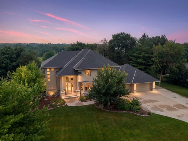 view of front of home with stucco siding, driveway, a front lawn, and stone siding