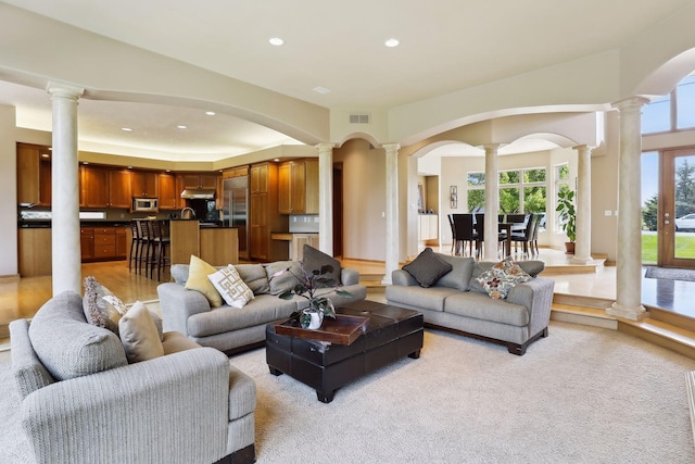 living area with light colored carpet, visible vents, arched walkways, ornate columns, and recessed lighting