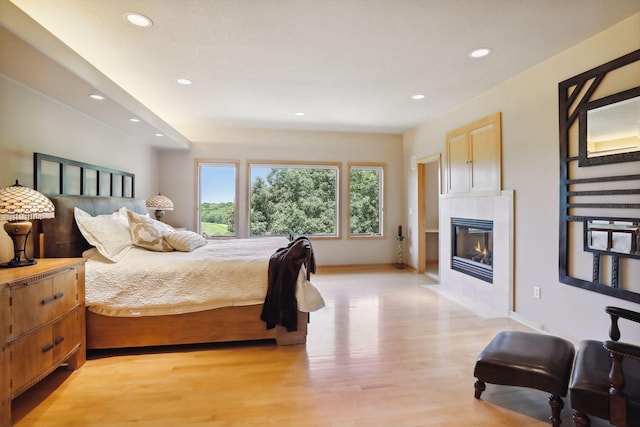 bedroom featuring recessed lighting, baseboards, light wood finished floors, and a tile fireplace