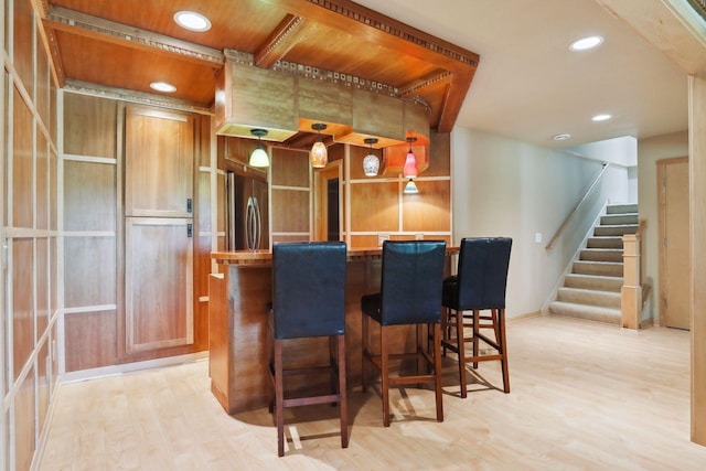 bar featuring recessed lighting, stainless steel fridge, light wood-style flooring, and stairway