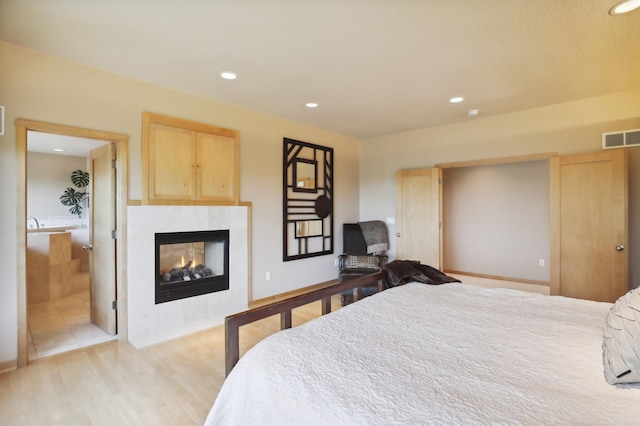 bedroom featuring recessed lighting, light wood finished floors, a tile fireplace, and visible vents