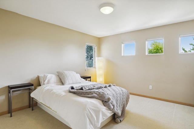 bedroom with baseboards and light carpet