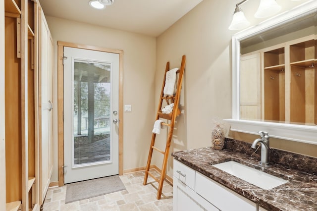 interior space featuring stone finish floor, baseboards, and vanity