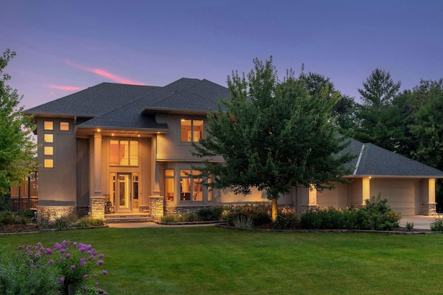 exterior space featuring a lawn, a shingled roof, and stone siding