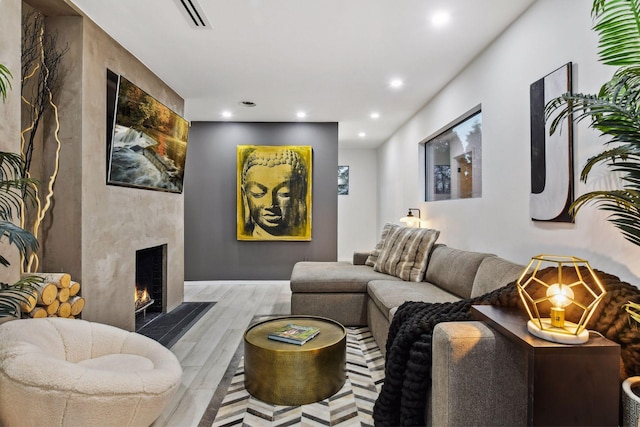 living room featuring recessed lighting, visible vents, a large fireplace, and wood finished floors