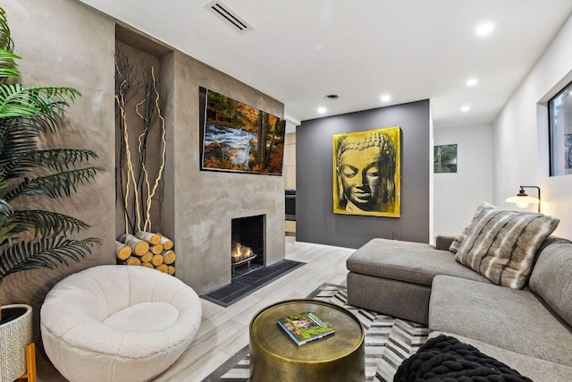 living area with recessed lighting, visible vents, a premium fireplace, and light wood-type flooring