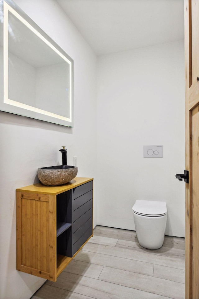 bathroom featuring toilet, wood finished floors, and vanity