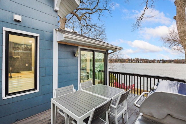 wooden terrace with a water view and outdoor dining area