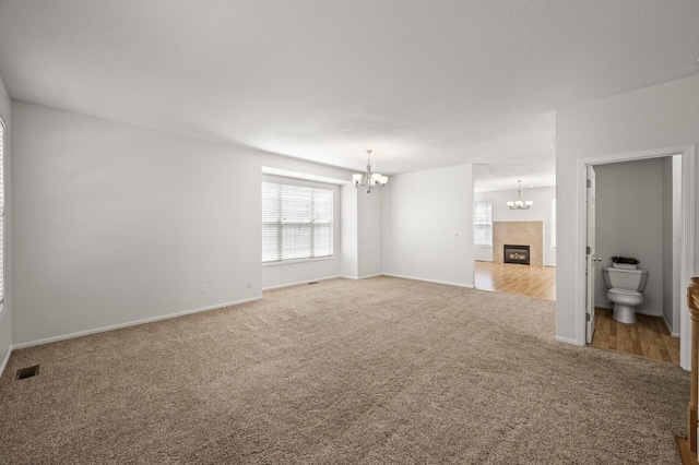 unfurnished living room featuring a wealth of natural light, visible vents, carpet, and a notable chandelier