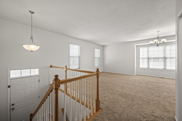carpeted entrance foyer with baseboards, a chandelier, and a healthy amount of sunlight