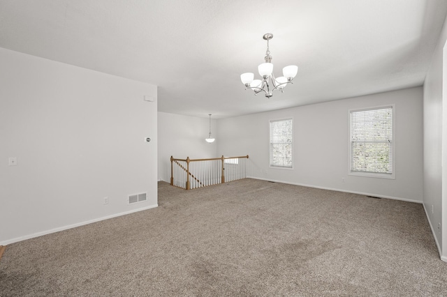 unfurnished room with a notable chandelier, visible vents, baseboards, and carpet