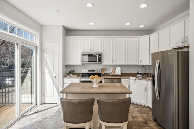 kitchen with stone tile floors, stainless steel appliances, a sink, and a center island