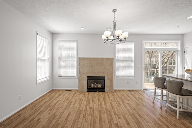 living area with an inviting chandelier, baseboards, light wood-type flooring, and a tile fireplace