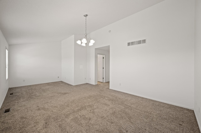 spare room featuring visible vents, an inviting chandelier, vaulted ceiling, and light colored carpet