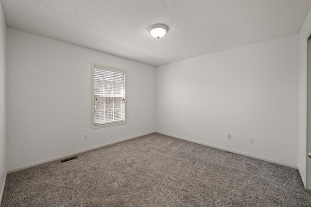 unfurnished room featuring baseboards, carpet flooring, a textured ceiling, and visible vents